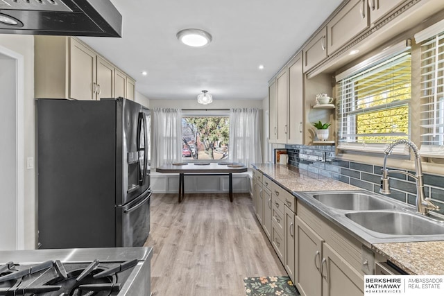 kitchen featuring fridge with ice dispenser, a sink, tasteful backsplash, ventilation hood, and light wood finished floors