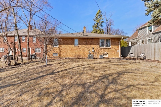 back of property featuring central air condition unit, brick siding, a lawn, and fence