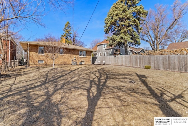 rear view of house featuring fence private yard, brick siding, and a chimney