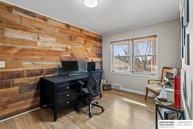 office space featuring visible vents, baseboards, wooden walls, and hardwood / wood-style floors