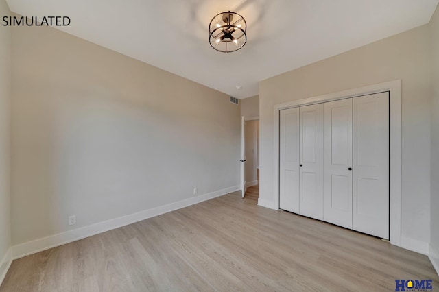 unfurnished bedroom with a closet, baseboards, visible vents, and light wood-style flooring