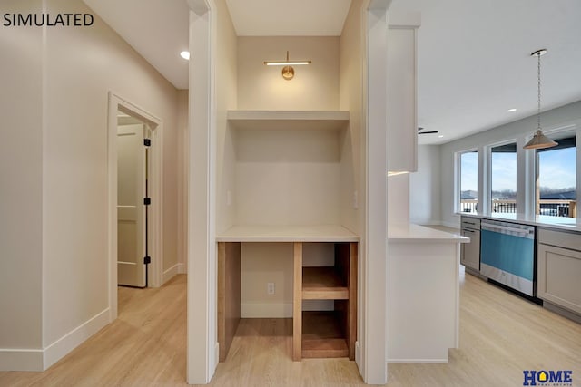 interior space featuring baseboards, light countertops, light wood-style floors, dishwasher, and decorative light fixtures