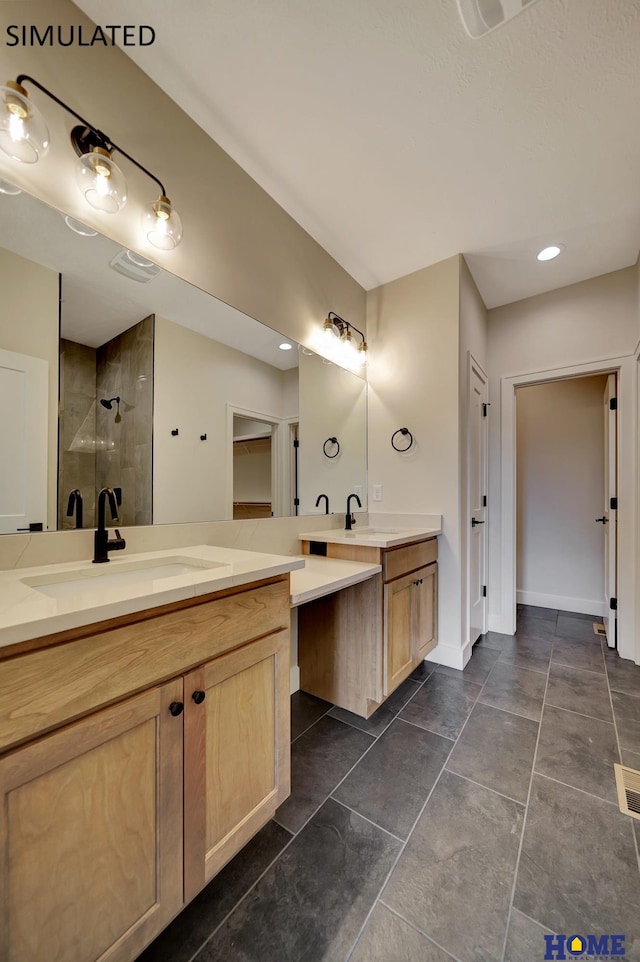 bathroom featuring a sink, baseboards, tiled shower, and two vanities