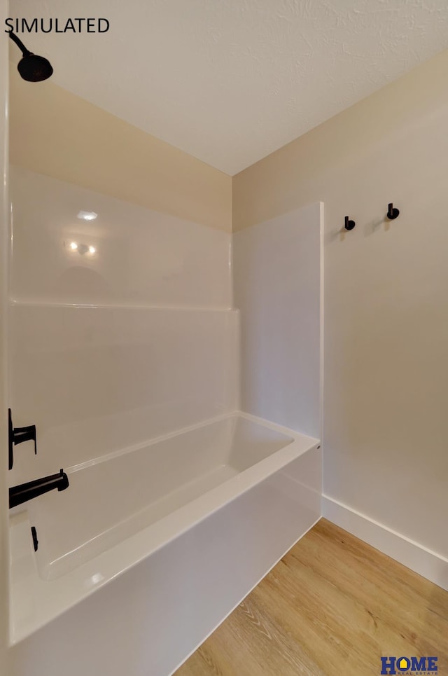 bathroom with tub / shower combination, baseboards, and wood finished floors