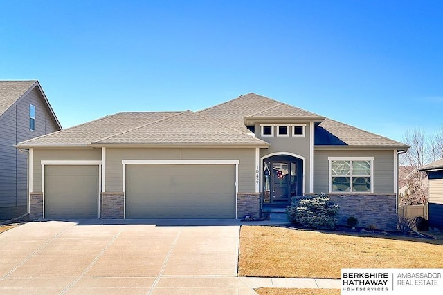 prairie-style home with a garage, stone siding, and concrete driveway