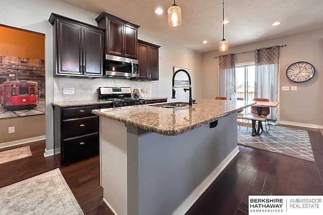 kitchen featuring a sink, stainless steel appliances, dark wood-type flooring, and backsplash