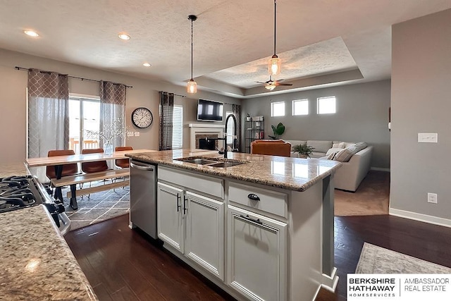 kitchen with dark wood-type flooring, open floor plan, a tray ceiling, a fireplace, and a textured ceiling