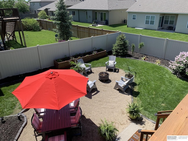 view of yard featuring an outdoor fire pit, a vegetable garden, a fenced backyard, a patio area, and a residential view