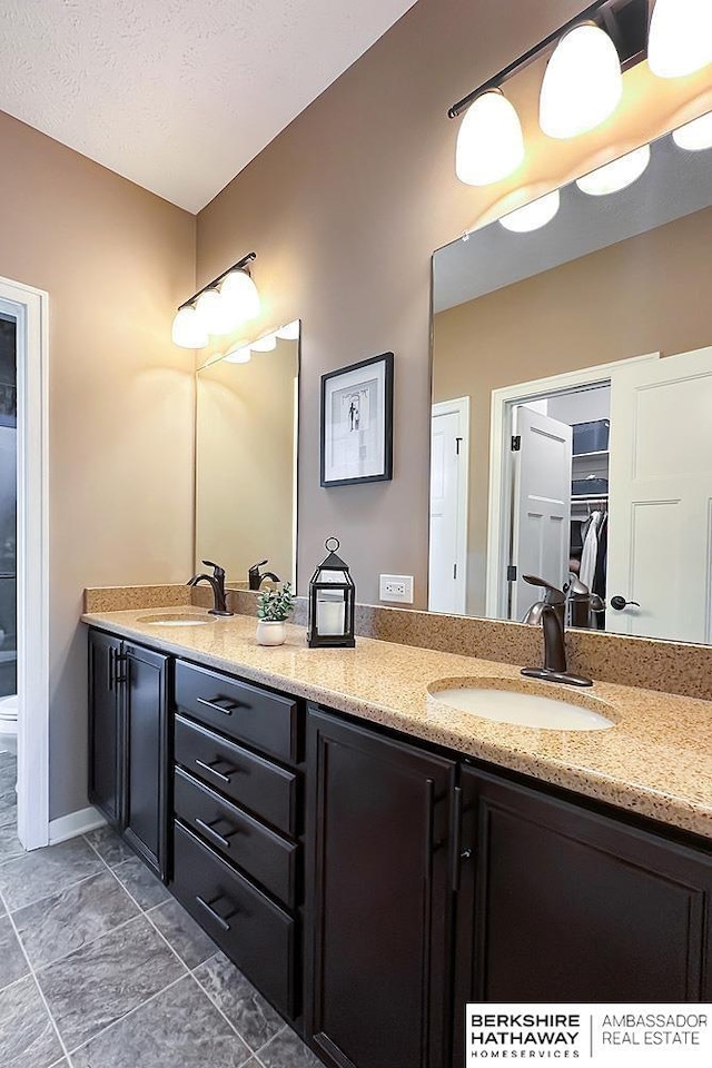 bathroom featuring a sink, a textured ceiling, and double vanity