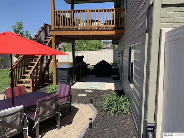 view of patio with outdoor dining space, stairway, fence, and a wooden deck