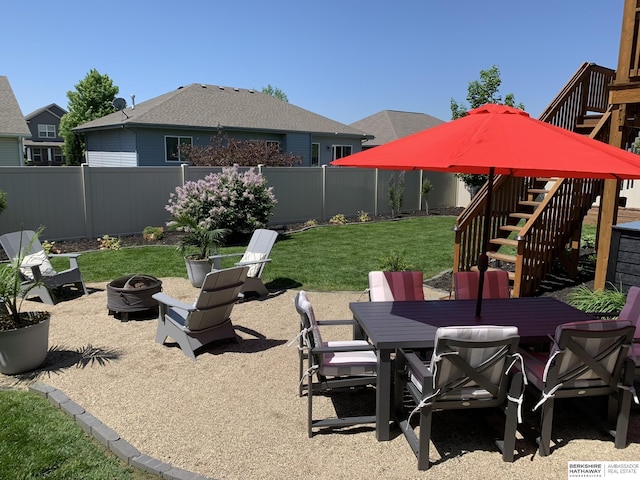 view of yard featuring outdoor dining space, a patio, a fenced backyard, an outdoor fire pit, and stairway