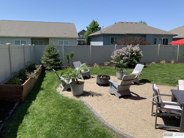 view of yard featuring a patio area, a fire pit, a vegetable garden, and fence