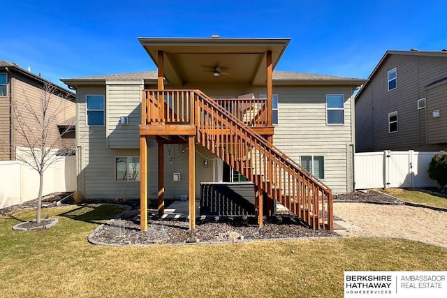 rear view of property with a deck, a gate, a fenced backyard, a yard, and stairway