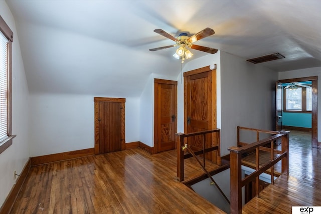 additional living space featuring visible vents, hardwood / wood-style flooring, baseboards, ceiling fan, and vaulted ceiling