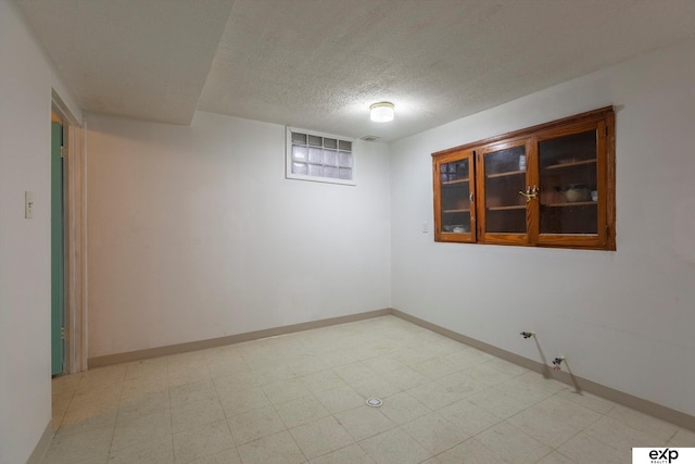 empty room featuring visible vents, light floors, baseboards, and a textured ceiling