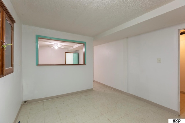 empty room featuring light floors, baseboards, and a textured ceiling