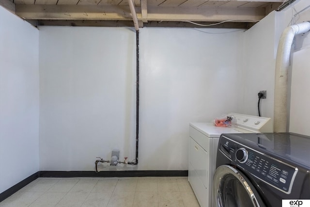 laundry area with laundry area, washing machine and dryer, and baseboards