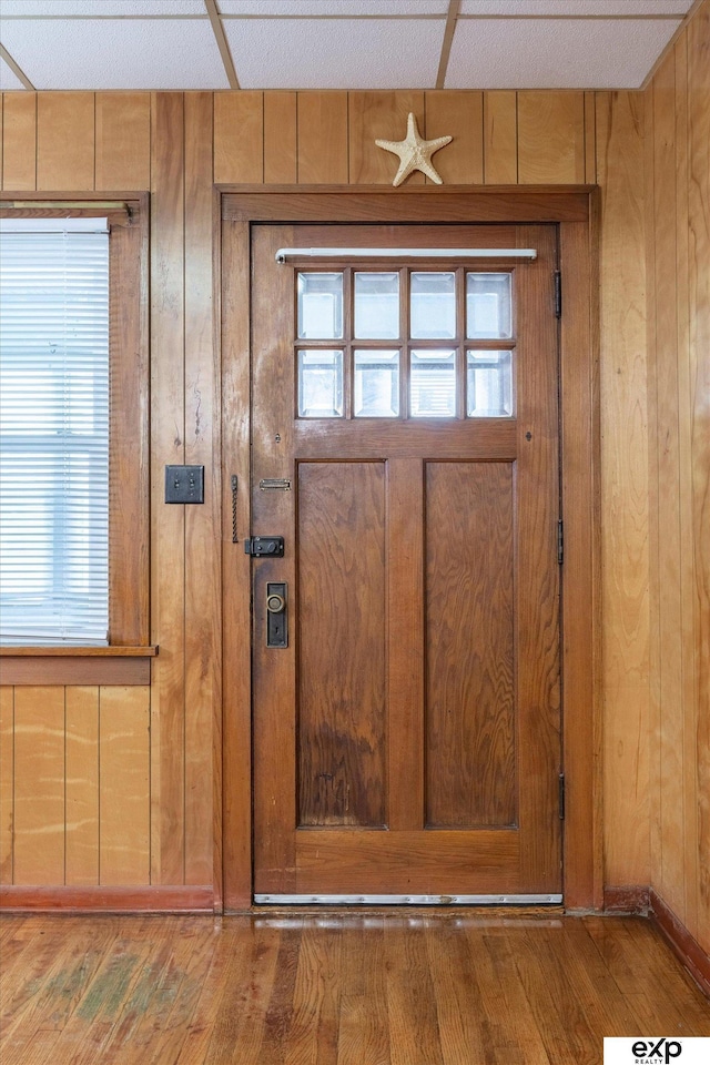 interior space featuring wooden walls, a paneled ceiling, and wood finished floors