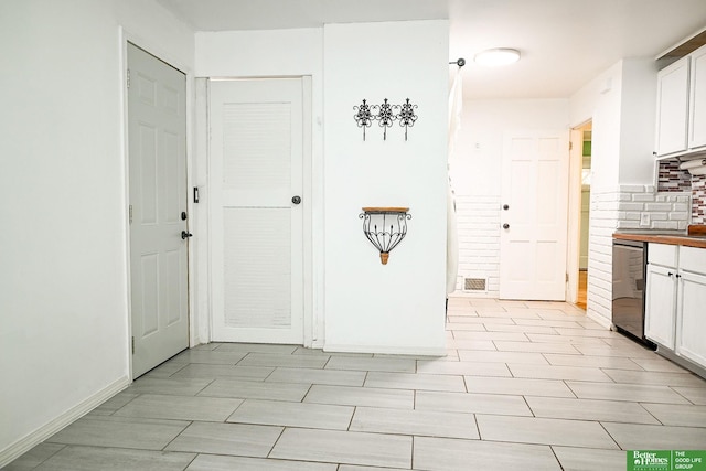 kitchen featuring dishwashing machine, baseboards, tasteful backsplash, and white cabinets