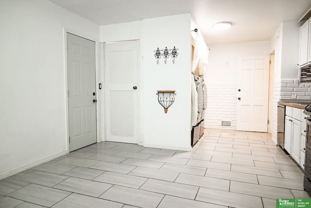 kitchen featuring visible vents, tasteful backsplash, fridge, white cabinets, and baseboards