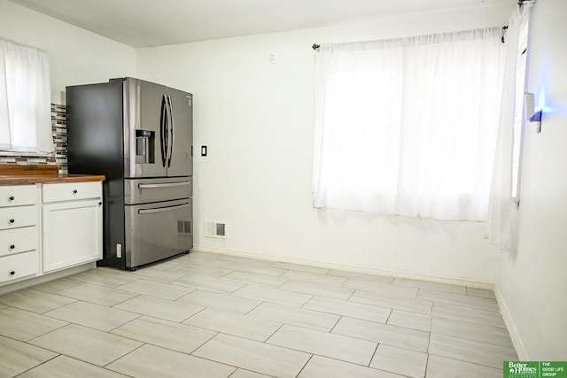 kitchen featuring visible vents, stainless steel fridge with ice dispenser, white cabinets, wood counters, and tasteful backsplash