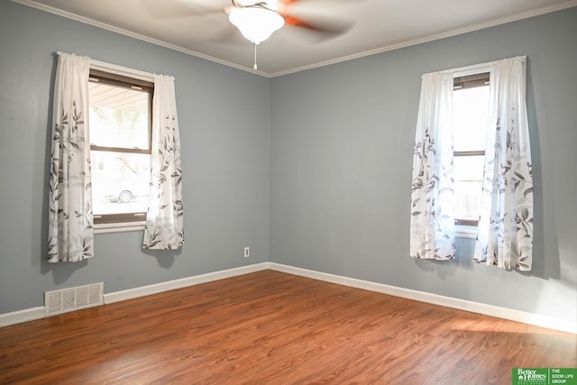 empty room featuring wood finished floors, visible vents, a wealth of natural light, and baseboards