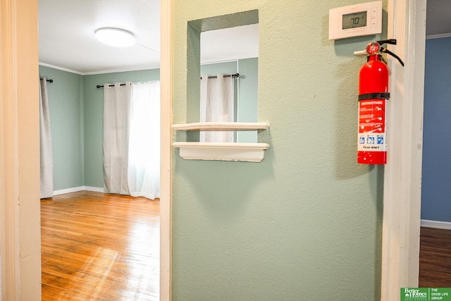 corridor with crown molding, wood finished floors, and baseboards