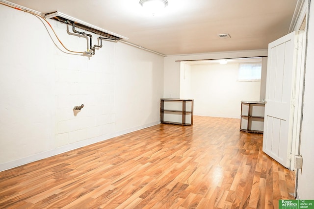 basement featuring visible vents, light wood-type flooring, and baseboards