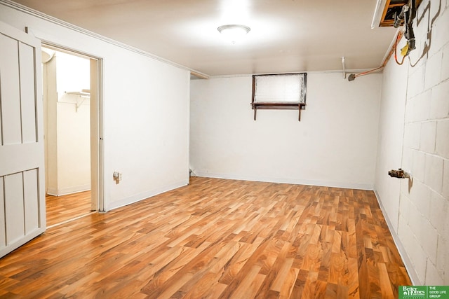 empty room featuring light wood-style floors, ornamental molding, and concrete block wall