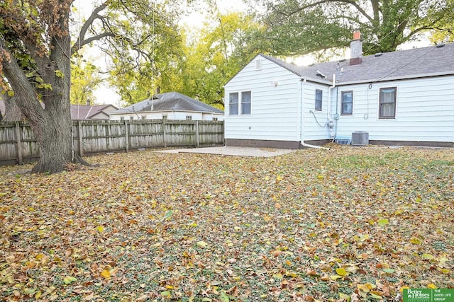 back of property with a patio, central air condition unit, a fenced backyard, and a chimney