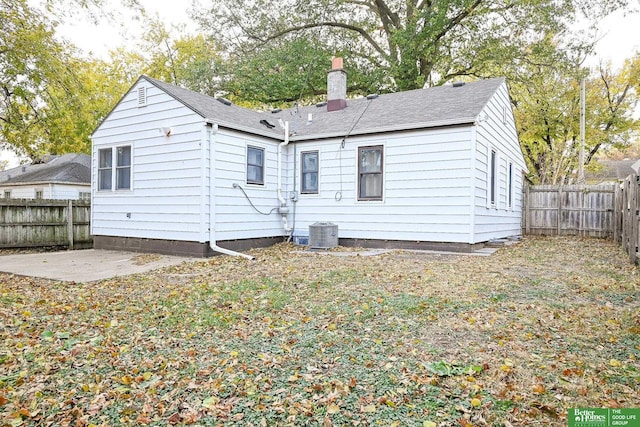 rear view of property featuring a patio, a fenced backyard, a chimney, and a shingled roof