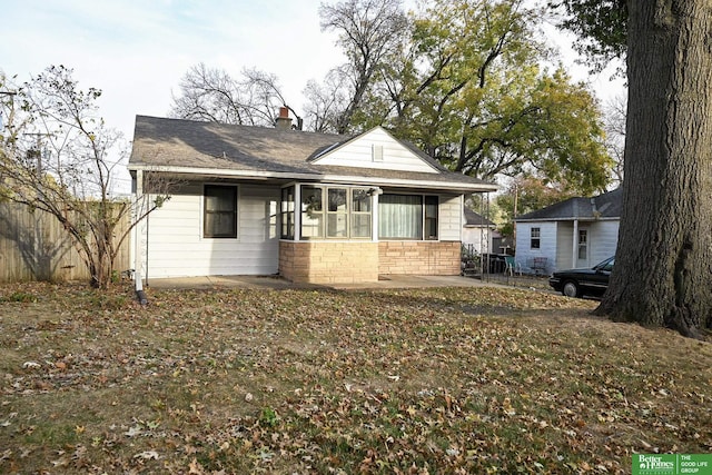 view of front facade featuring a patio, stone siding, and a chimney