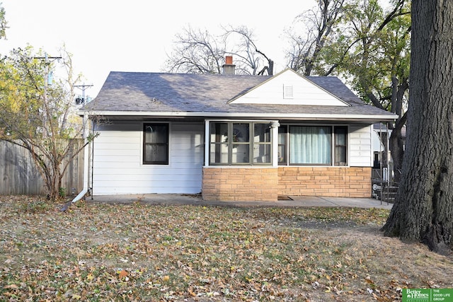 bungalow-style house featuring stone siding, a chimney, and fence