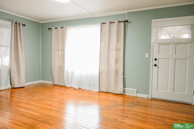 interior space featuring crown molding, visible vents, baseboards, and wood-type flooring