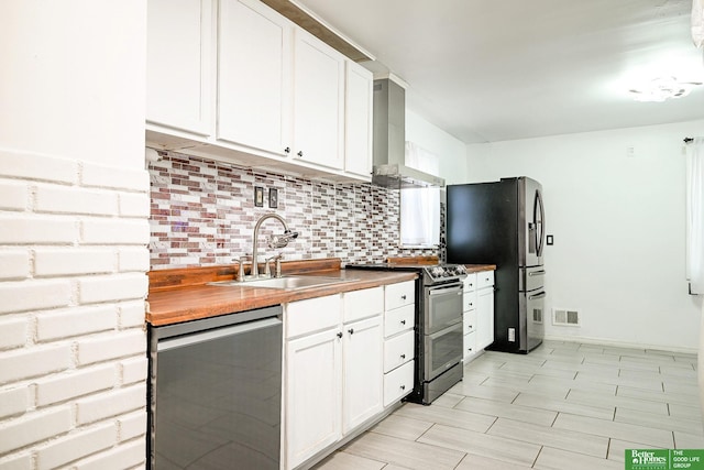 kitchen with visible vents, a sink, decorative backsplash, appliances with stainless steel finishes, and wall chimney exhaust hood