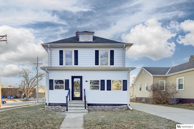 american foursquare style home with a front lawn and roof with shingles