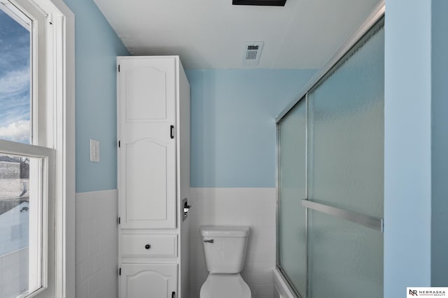 full bathroom with visible vents, tile walls, an enclosed shower, and wainscoting