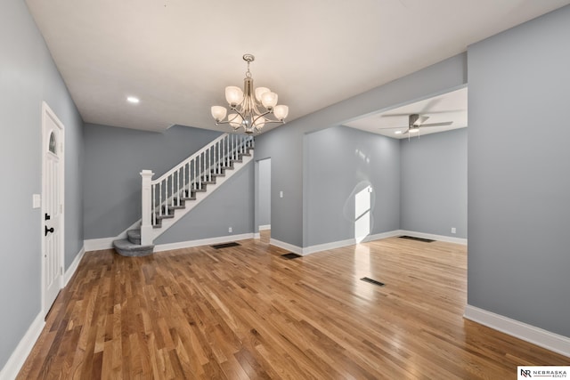 interior space with stairway, wood finished floors, visible vents, baseboards, and ceiling fan with notable chandelier