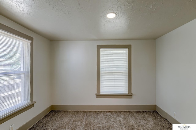 carpeted spare room with a textured ceiling and baseboards