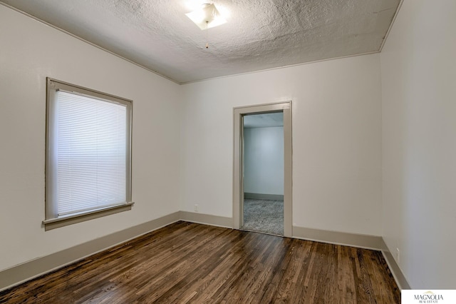 unfurnished room featuring dark wood-style floors, a textured ceiling, and baseboards