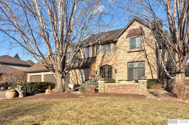 view of front of property with a front yard, a garage, and brick siding