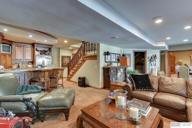 living area featuring stairway, baseboards, recessed lighting, indoor wet bar, and light carpet