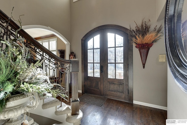 entrance foyer featuring wood finished floors, french doors, arched walkways, and a wealth of natural light