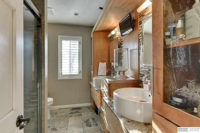 bathroom featuring visible vents, baseboards, toilet, vanity, and a textured ceiling