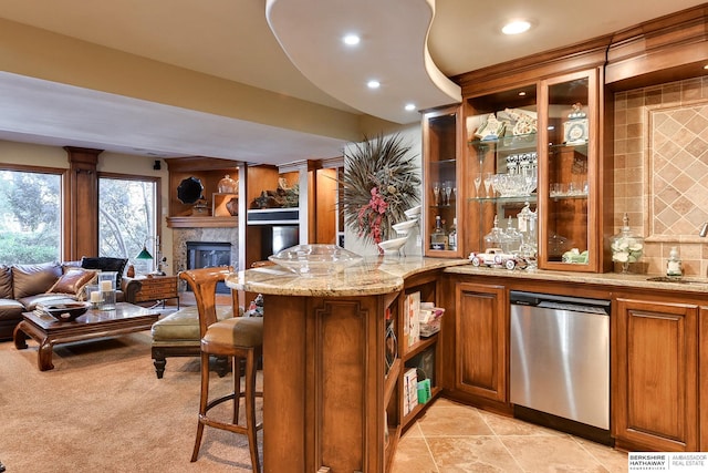 bar featuring a sink, a glass covered fireplace, decorative backsplash, indoor bar, and dishwasher