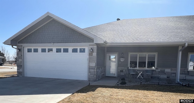 view of front facade featuring stone siding, concrete driveway, an attached garage, and a shingled roof