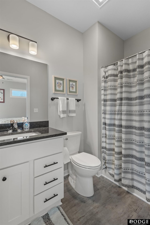 bathroom featuring visible vents, curtained shower, toilet, wood finished floors, and vanity