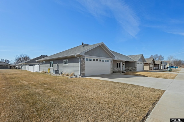 view of side of property featuring central air condition unit, concrete driveway, a garage, a yard, and stone siding