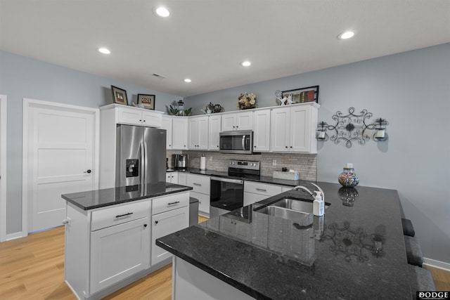 kitchen with decorative backsplash, light wood finished floors, appliances with stainless steel finishes, and a sink