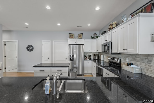 kitchen featuring backsplash, white cabinets, stainless steel appliances, and a sink